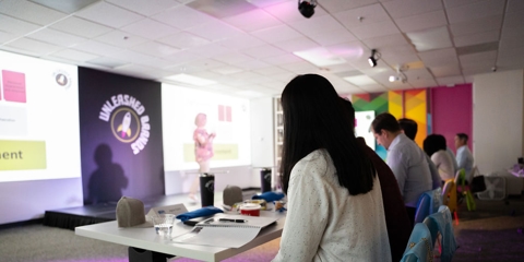 Woman listening to presenter talk on stage
